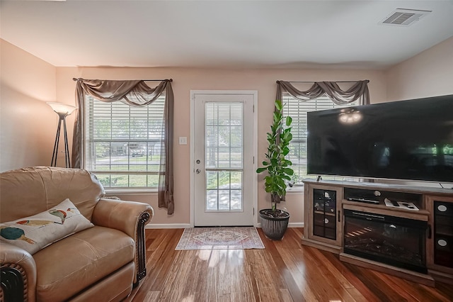 living room featuring wood finished floors, visible vents, and baseboards