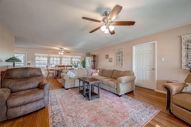 living area with baseboards, a ceiling fan, and wood finished floors