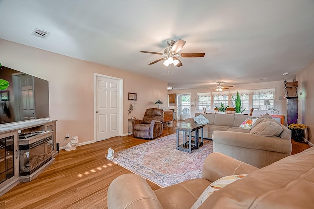 living room with visible vents, ceiling fan, light wood-style flooring, and baseboards