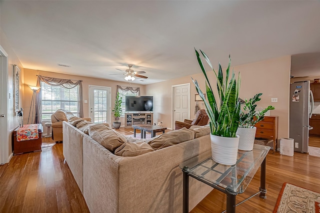 living area with a ceiling fan, visible vents, and wood finished floors