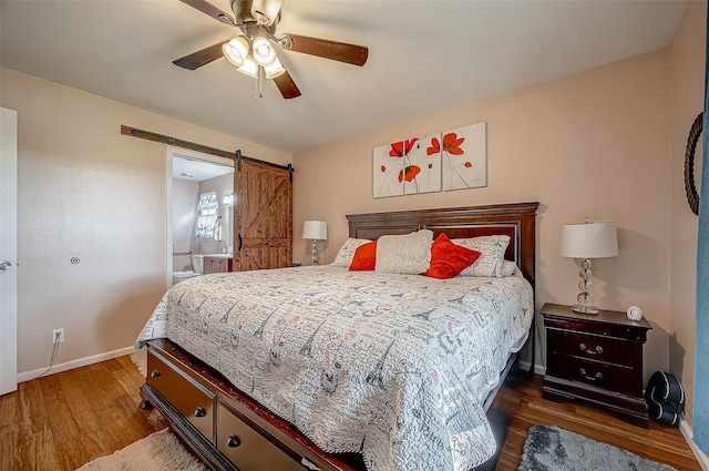 bedroom featuring ceiling fan, a barn door, wood finished floors, and baseboards