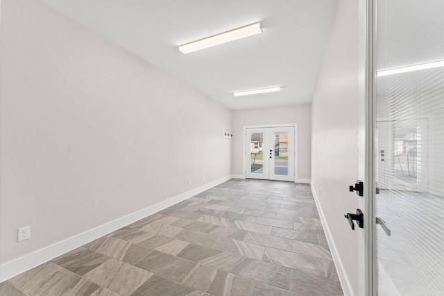 unfurnished room featuring french doors and baseboards