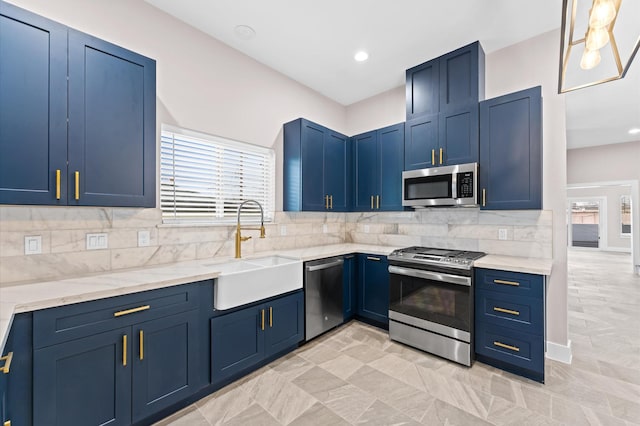 kitchen featuring backsplash, light stone countertops, appliances with stainless steel finishes, blue cabinets, and a sink