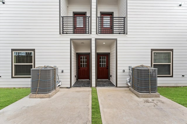 entrance to property with a balcony, central air condition unit, and a patio