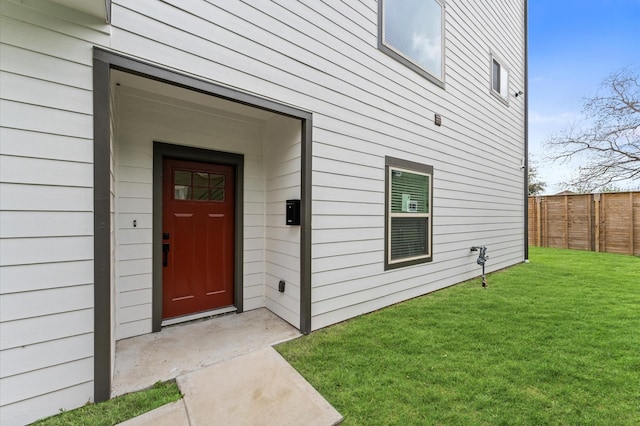 doorway to property featuring a lawn and fence