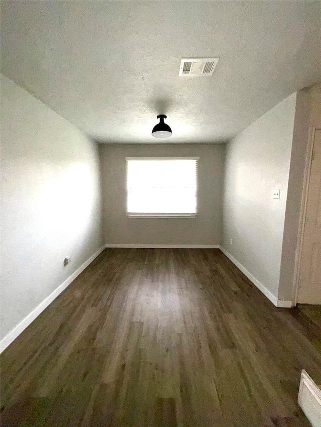 unfurnished room with baseboards, a textured ceiling, visible vents, and wood finished floors