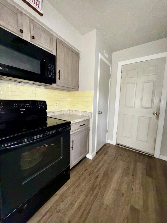 kitchen with dark wood-style flooring, tasteful backsplash, light countertops, black appliances, and baseboards