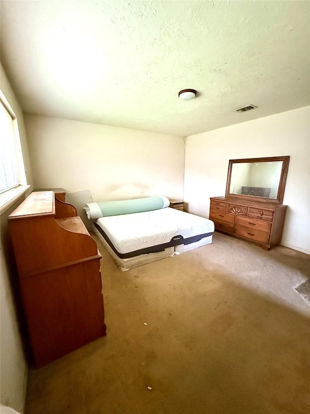 unfurnished bedroom with carpet flooring, visible vents, and a textured ceiling