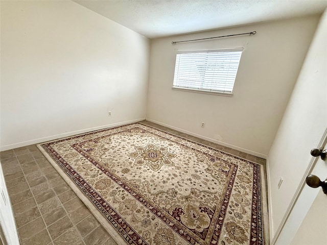 unfurnished room with a textured ceiling and baseboards