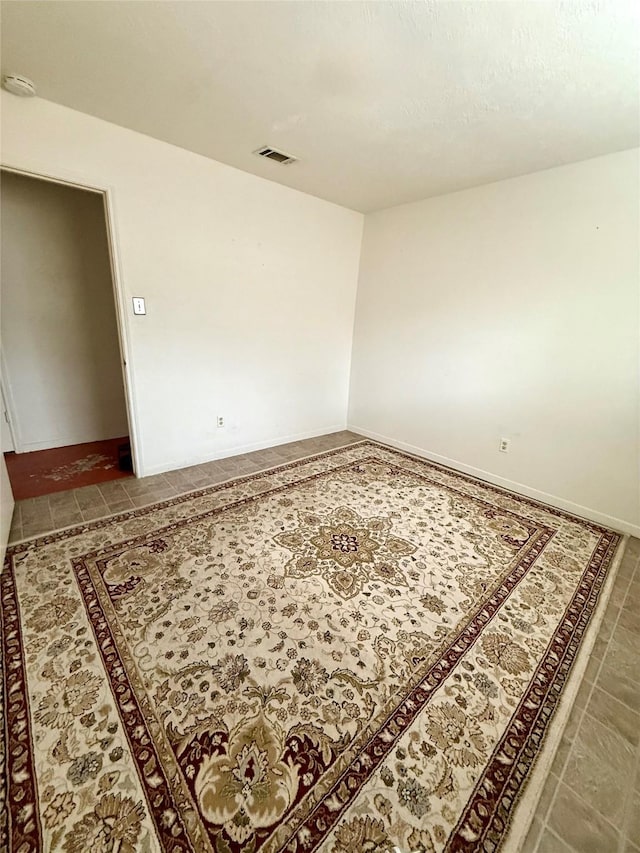 tiled spare room featuring visible vents and baseboards