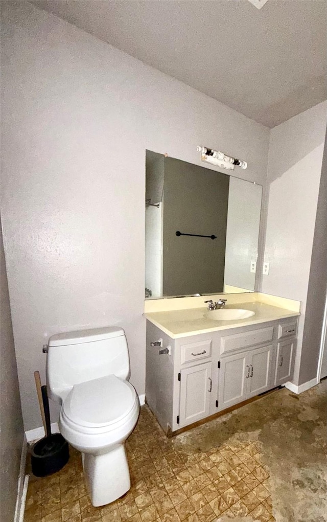 bathroom featuring baseboards, vanity, and toilet