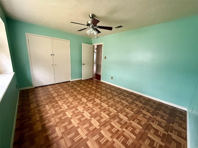 unfurnished bedroom with baseboards, visible vents, a ceiling fan, a textured ceiling, and a closet