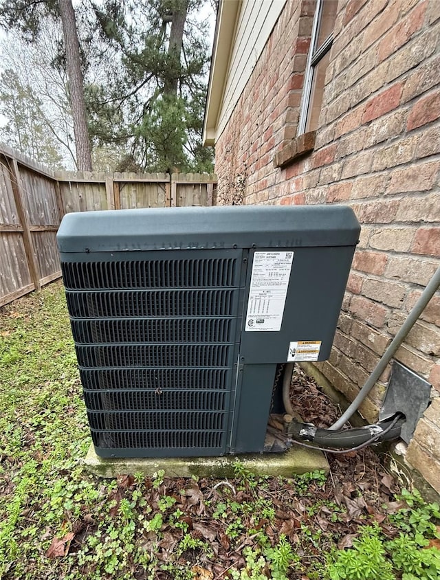 exterior details with brick siding, fence, and central air condition unit