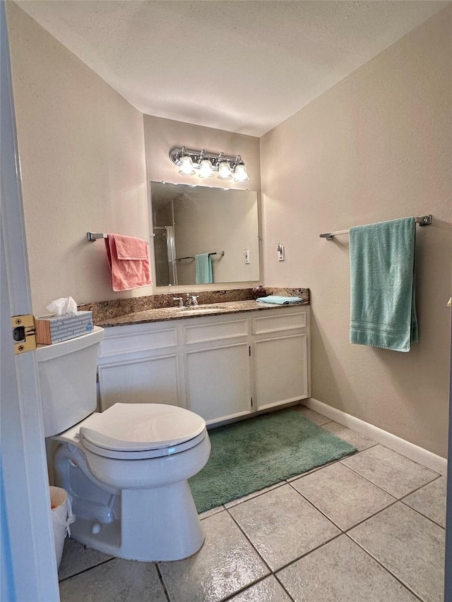 bathroom with a shower with shower door, toilet, vanity, baseboards, and tile patterned floors