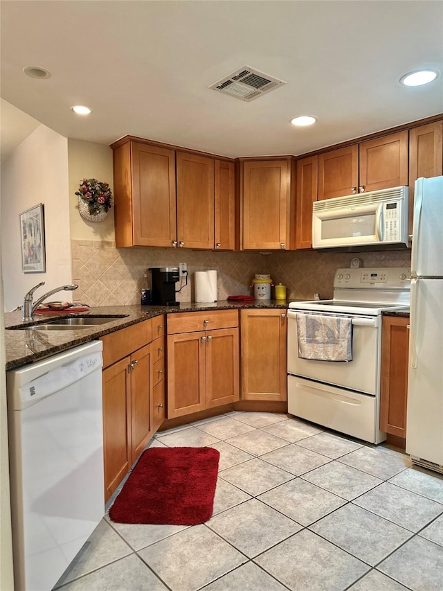 kitchen with tasteful backsplash, visible vents, brown cabinetry, a sink, and white appliances