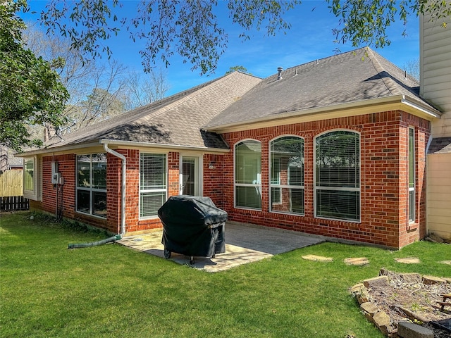 back of property with a patio area, a shingled roof, a yard, and brick siding