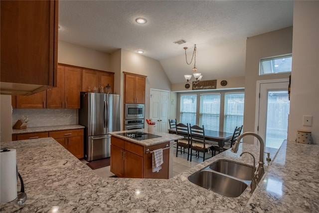 kitchen featuring visible vents, a sink, appliances with stainless steel finishes, brown cabinetry, and light stone countertops