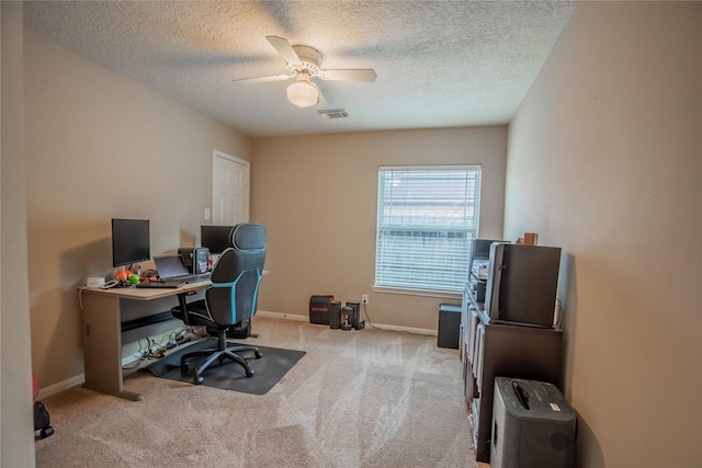 carpeted office with visible vents, a textured ceiling, baseboards, and ceiling fan