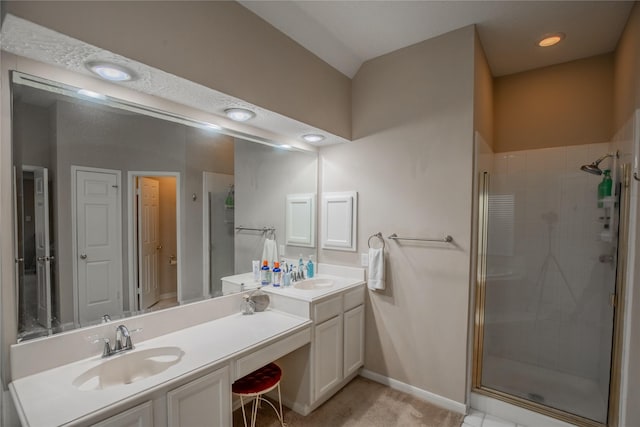 bathroom featuring double vanity, a stall shower, and a sink