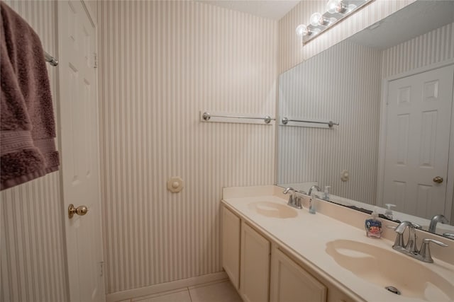 full bath featuring tile patterned floors, double vanity, wallpapered walls, and a sink