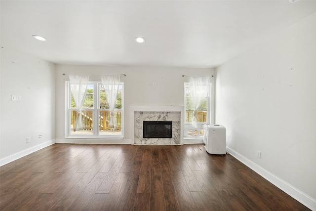 unfurnished living room featuring recessed lighting, baseboards, wood finished floors, and a high end fireplace