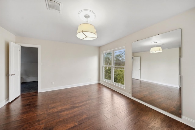 empty room with visible vents, baseboards, and hardwood / wood-style floors
