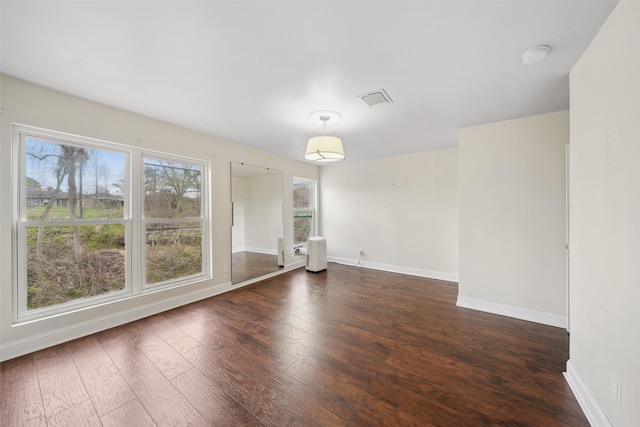 empty room with visible vents, baseboards, and hardwood / wood-style flooring