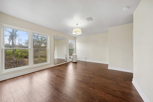 empty room featuring visible vents, baseboards, and wood finished floors