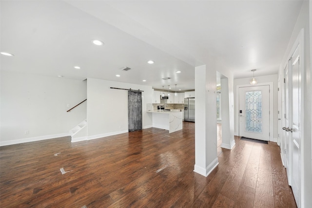 entryway with dark wood-style floors, visible vents, baseboards, recessed lighting, and a barn door