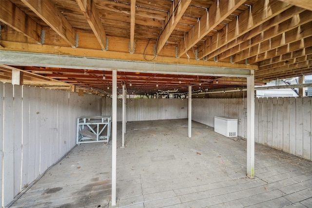 unfinished basement featuring wooden walls, refrigerator, and hardwood / wood-style flooring