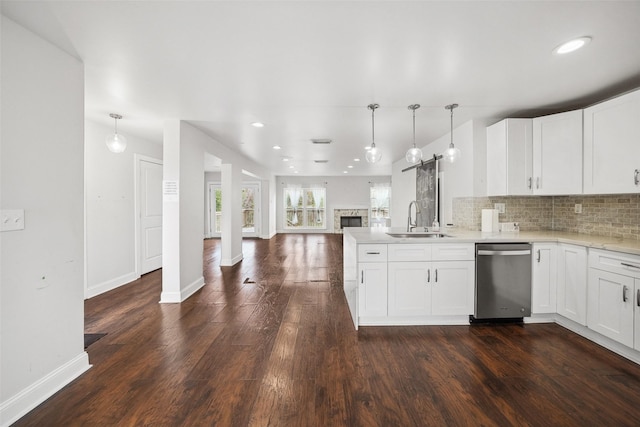 kitchen with a peninsula, a sink, dishwasher, open floor plan, and backsplash