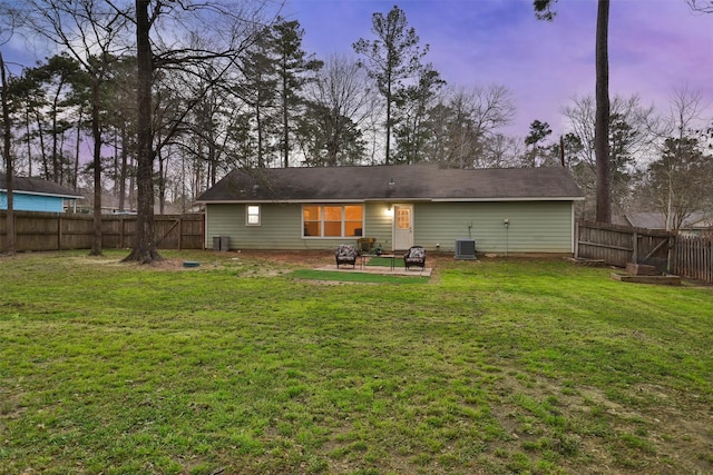 rear view of house with a patio, a lawn, cooling unit, a fenced backyard, and a fire pit