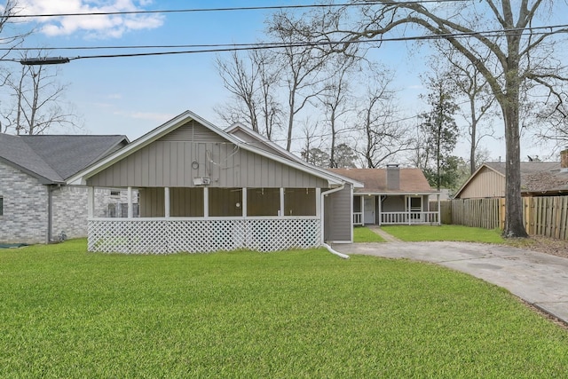 back of property with driveway, covered porch, fence, and a yard