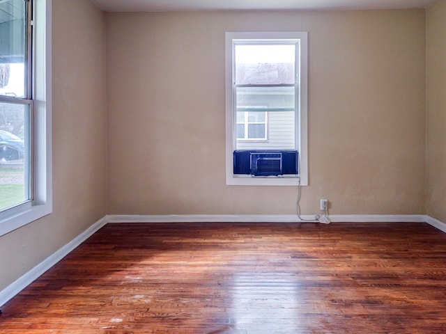 unfurnished room featuring cooling unit, plenty of natural light, wood finished floors, and baseboards