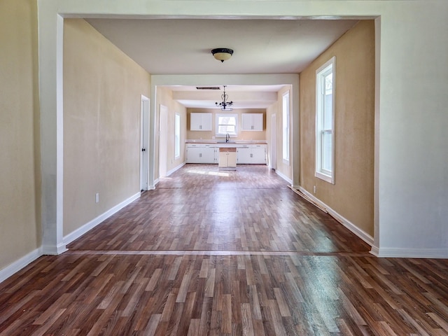 unfurnished living room with a sink, dark wood finished floors, and baseboards