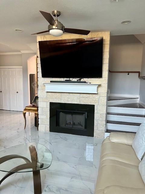 living area featuring marble finish floor, a fireplace, and crown molding