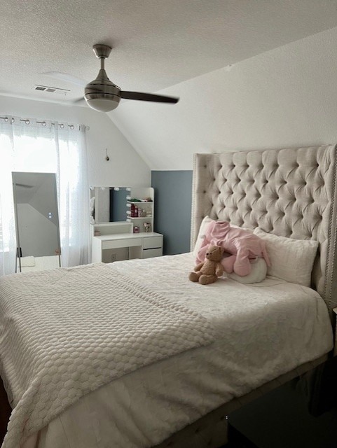 bedroom with lofted ceiling, ceiling fan, a textured ceiling, and visible vents