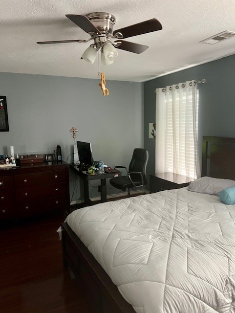 bedroom with visible vents, dark wood finished floors, a textured ceiling, and ceiling fan