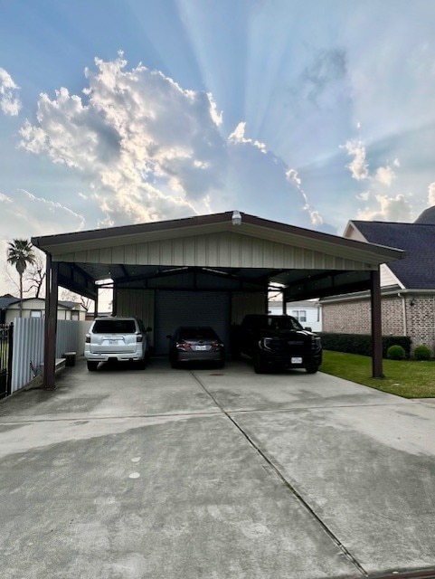 view of car parking with a carport, concrete driveway, and fence