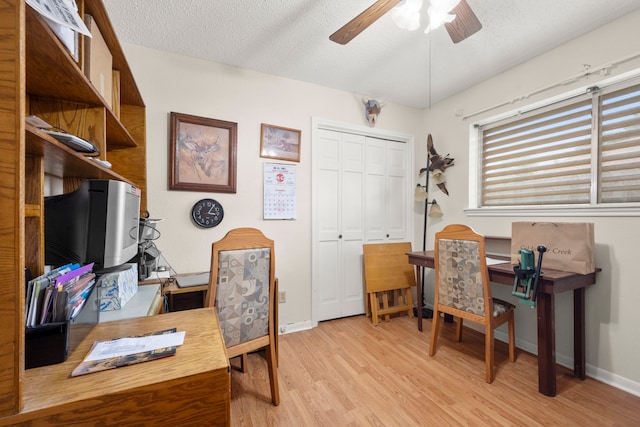 office space featuring a textured ceiling, light wood finished floors, a ceiling fan, and baseboards