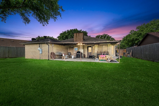 rear view of property featuring a yard, a fenced backyard, and a patio