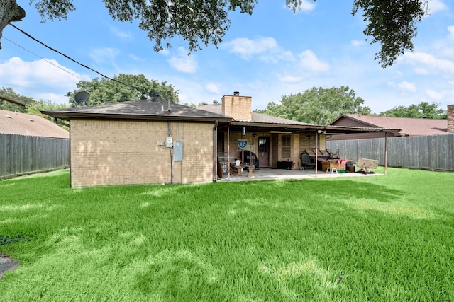 rear view of property with a yard, brick siding, a chimney, and a patio area