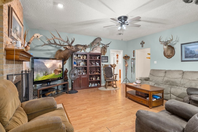 living room with a textured ceiling, a ceiling fan, and wood finished floors