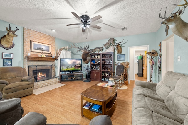 living room featuring a textured ceiling, a fireplace, and wood finished floors