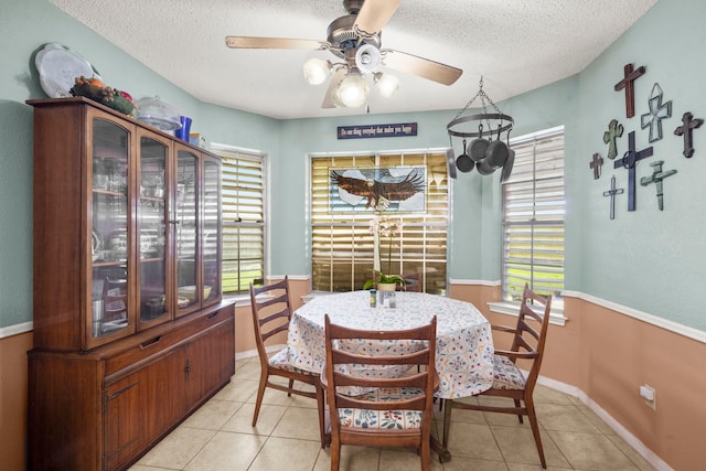 dining room featuring light tile patterned floors, ceiling fan, a textured ceiling, and baseboards