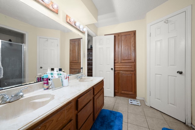 full bath with double vanity, a stall shower, a sink, and tile patterned floors