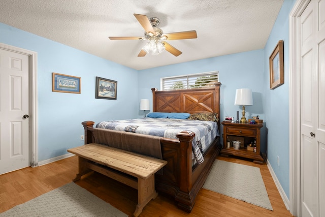 bedroom featuring light wood-type flooring, a textured ceiling, and baseboards