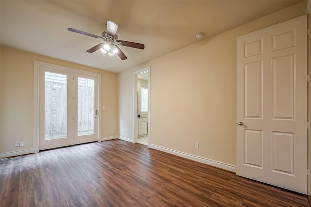 empty room featuring a ceiling fan, dark wood finished floors, and baseboards