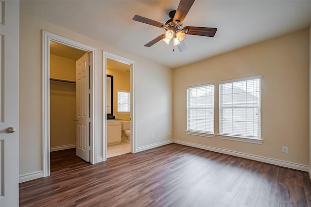 unfurnished bedroom featuring dark wood-type flooring, a closet, multiple windows, and a spacious closet