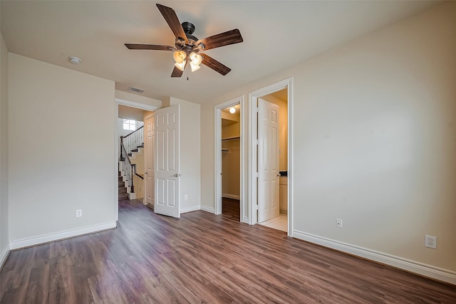 unfurnished bedroom featuring wood finished floors, a ceiling fan, visible vents, baseboards, and a spacious closet